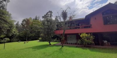 Espectacular casa de 634 m² construidos en un lote de 7.644 m², rodeada de naturaleza y amplias zonas verdes.

En el primer nivel cuenta con sala de estar, sala comedor independiente, dos chimeneas, estudio con salida al jardín, alcoba principal con estudio privado, walking closet y baño con tina, además de dos cocinas, despensa, dos zonas de lavandería, cuarto y baño de servicio, cuarto de conductores y patio.

En el segundo nivel dispone de 2 alcobas, cada una con baño, sala de estar, área de depósito y salida directa a las zonas verdes.

La casa ofrece espacio para 4 garajes cubiertos y 8 descubiertos, 2 cuartos de herramientas, pozo, huerta, áreas verdes y sistema de motobombas. Su ubicación es estratégica, cerca de la escuela de carabineros, en un entorno tranquilo y seguro.