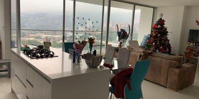 Apartamento en venta ubicado en Suramérica, Itagüí, con un área total de 110 M2. La propiedad cuenta con 3 alcobas, cada una con closet, además de un vestier en la alcoba principal. Dispone de un amplio salón comedor con acceso a un balcón grande que ofrece una vista despejada hacia la zona sur. Incluye una sala auxiliar, comedor adicional, estudio y una cocina integral abierta con mesón en quarztone, equipada con lavavajillas y conexiones para domótica. Tiene 3 baños modernos con cabinas en vidrio templado, zona de ropas con red de gas y calentador. El apartamento también incluye 2 parqueaderos sencillos y 3 cuartos útiles (dos en el mismo piso del apartamento y uno en uno de los parqueaderos). Está ubicado en el piso 21 de un edificio entregado en octubre de 2020.

La unidad residencial ofrece seguridad con portería las 24 horas, citófono, circuito cerrado de TV, ascensor y shut de basuras. Entre las zonas comunes destacan las amplias zonas verdes, gimnasio, salón social, piscinas,