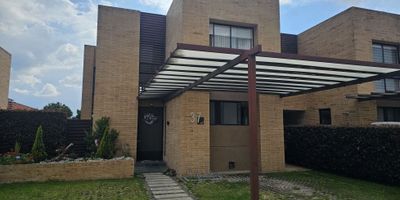 CODIGO: 8961FR888 ¡Impresionante Casa Campestre en Cajicá! Con más de 300 m² de lote, esta propiedad combina diseño moderno, funcionalidad y un entorno natural que te encantará.Características del inmueble:


 Área construida: 190 m²
 Área privada: 163.12 m²
 Área del lote: 387.26 m²


Primer nivel:


 Entrada con pérgola que cubre 4 parqueaderos privados, incluyendo un punto de carga para vehículo eléctrico.
 3 accesos: puerta principal y dos entradas a los jardines.
 Sala con chimenea, comedor y estar de TV en un concepto abierto.
 Cocina tipo americana con isla, moderna y funcional.
 Cuarto de lavandería independiente y depósito.
 Amplio jardín en forma de "U" que rodea la casa.
 Baño social y escalera al segundo nivel.


Segundo nivel:


 Espacioso estudio con terraza.
 Hall de habitaciones y 3 habitaciones, todas con baño privado.
 
  La habitación principal incluye walking closet y baño con doble lavamanos.
  Las habitaciones auxiliares cuentan con balcón.
 
 


Áreas sociales del conjunto:


 Portería y vigilancia privada con circuito cerrado.
 Zonas deportivas: cancha de tenis, fútbol y baloncesto.
 Gimnasio, sala de negocios, salón comunal y sala de proyecciones.
 Zona de BBQ, juegos infantiles, turco, sauna y bicicletero.
 Amplias zonas verdes y tanque de agua para mayor comodidad.


¡Un hogar que combina lujo, naturaleza y entretenimiento en un solo lugar!
