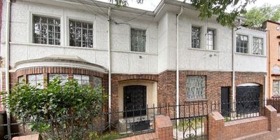 Casa de dos niveles con arquitectura representativa y declaratoria de bien de interés cultural, ideal para restaurar con visión patrimonial. Su distribución ofrece áreas generosas, excelente iluminación natural y elementos originales como pisos en madera, ventanales curvos, chimenea tradicional y puertas macizas. El primer nivel cuenta con amplias zonas sociales, comedor independiente, cocina cerrada con acceso a patio, baño auxiliar, cuarto auxiliar y un jardín posterior perfecto para ambientar o ampliar funcionalmente. En el segundo nivel se encuentra un hall distribuidor, habitaciones con techos altos y un baño principal en estilo clásico. La propiedad incluye un parqueadero cubierto interno. Ideal para proyectos culturales, co-living, oficinas creativas o residencia familiar con carácter. Ubicada en entorno de alta valorización y entorno universitario, con facilidad de acceso y entorno arborizado.