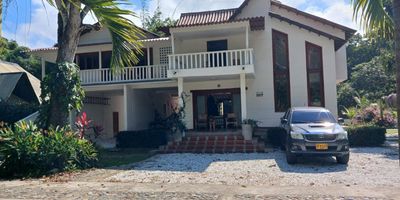 VENTA Ó PERMUTA POR CASA ARMENIA. Una Casa de lujo en Santa Marta de 194 M2 en lote de 6.335 M2 , Sector del Parque Tayrona. DETALLES:  Excelente inversión para hotelería y turismo, rentas cortas.  Se encuentra en sector turístico, con acceso directo a la vía principal.  Tiene 2 pisos, con 7 amplias habitaciones, Tiene Casa de Huéspedes, Quiosco con BBQ, ¨Piscina y acceso directo al hermoso Río Piedra con jardines y árboles frutales.  PRIMER PISO.  Sala, comedor, biblioteca, cocina con vista al río, baño social y hall de hamacas. Tiene acceso a una amplia zona de estar con mirador y piscina con duchas. SEGUNDO PISO.  4 habitaciones, con baño, aire acondicionado, closets y dos balcones.  closets y 2  balcones.
Incluye Apartamento, con Sala-comedor y Cocina, Parqueadero cubierto lineal para dos carros y deposito.  En el segundo piso tres habitaciones con baño, aire acondicionado y balcones.  transformador propio de 25 KVA y generador eléctrico.  Precio $2,050 millones COP / $512.500 USD.
