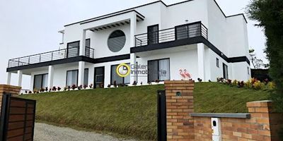 Casa en Venta en la Mesa de los Santos cuenta con 8 alcobas, 9 baños, sala comedor, cocina integral, 10 parqueaderos. adicional, los techos de la casa y salón social cuentan con un diseño técnico para recolección de agua de lluvia de 320 metros cúbicos para uso en riego de la zona verde más 2 tanques de almacenamiento de agua subterráneos independientes con una capacidad total de más de 40 mil litros. a parte, dispone de un área externa con zona de BBQ, prado japonés, domo acrílico, con isla de mostrador, lavavajillas y con un amplio tanque para reserva de suministro de gas propano.