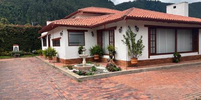 CAJICÁ CASA NO ADOSADA, en conjunto cerrado, Cuenta con una maravillosa vista a las montañas y al paisaje sabanero que la rodea. Tiene un área construida de 414 m² distribuidos así: 268 m² corresponden a la casa y 146 m² a la zona de BBQ sobre un lote de 786 m². Con muy buenos acabados y amplia zona de parqueo. DISTRIBUCIÓN CASA PRIMER PISO: Hall de acceso, Sala independiente con gran chimenea, comedor, cocina abierta con isla, zona de lavandería independiente, estudio, baño social, tres alcobas cada una con baño: SEGUNDO PISO: Alcoba principal con baño, vestier y terraza ZONA DE BBQ: Cuenta con un área de construcción de 148 m² cubiertos y cerrados, equipado con mesones, lavaplatos, horno. Amplios espacios y grandes ventanales.La casa se caracteriza por tener excelente entrada de sol. Los espacios interiores son de gran tamaño. Hermosos jardines, cerramiento, con cerca viva.