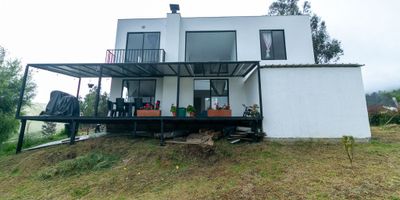 En el corazón de una zona productiva del municipio de Sesquilé-Cundinamarca, se encuentra esta impresionante casa en arriendo. En un área de 200 mts2 de construido de 1256 mts2 en total y con una arquitectura moderna, esta propiedad ofrece un espacio amplio y muy confortable distribuido en dos plantas. En la primera planta se encuentra la sala -comedor con chimenea, cocina amplia tipo americano, patio de ropas, un baño social, una habitación auxiliar, estudio y una bodega. En la segunda planta se encuentra tres habitaciones, la habitación principal con balcón, baño amplio con tuberías y espacio para instalar un jacuzzi y dos habitaciones amplias y un baño. El terreno cuenta con portón, cerca viva, dos invernaderos, uno de ellos con tubería y tanques listo para usar, cámaras y reflectores, dos jaulas para perros. Esta propiedad es ideal para desarrollar un proyecto productivo o para disfrutar de los placeres y la tranquilidad que ofrece el campo.