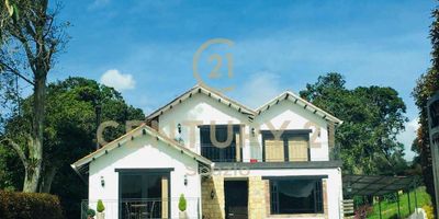 Te invitamos a conocer esta linda y confortable casa campestre, ubicada en la zona de Río Frío Oriental de Tabio. Al cruzar la puerta automática de acceso, nos encontramos con una gran zona verde con camino de entrada adoquinado para vehículos y vista hacia la fachada de la casa, sus dos terrazas frontales y antejardín. Ingresando a la casa, tenemos el amplio hall de entrada; a su derecha, accedemos a un primer espacio social, acondicionado actualmente como una cómoda e iluminada sala de TV. Hacia la izquierda, nos dirigimos a la habitación principal que cuenta con chimenea, terraza con vista panorámica a las montañas, vestier con luz natural y baño privado con jacuzzi, ducha, doble lavamanos e iluminación y ventilación directa.  Cruzando el corredor, se encuentra a un costado el estudio y camino de entrada a la zona social y cocina y hacia el otro costado, el  baño auxiliar, la zona de lavandería y escaleras de acceso al segundo piso.  La zona social es un amplio y acogedor espacio a doble altura, integrado por la sala con chimenea, comedor y una moderna cocina abierta, acondicionada con suficientes muebles de almacenamiento e isla central. Todo este espacio, iluminado por una puerta ventana que da salida a la terraza cubierta con pérgola de vidrio y al jardín posterior de la casa. En el segundo piso, se encuentra ubicado un hall que bordea las dos habitaciones superiores, contando cada una con baño privado y puertas ventanas que conducen a terrazas privadas con una vista espectacular de las montañas y el atardecer.  Esta propiedad se complementa con un parqueadero cubierto y espacio para 4 vehículos adicionales, tanques de reserva para agua potable y de aguas lluvias, sistema hidráulico de bombeo, pozo de agua y cámaras de vigilancia. Adicionalmente, existe la opción de venta con muebles y electrodomésticos.