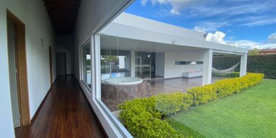 Casa en venta en la parcelacion Prado Verde, Llanogrande. Lote de mil quinientos cincuenta metros cuadrados y construccion de trescientos cincuenta metros en un solo nivel. Diseno moderno con acabados de lujo. Cuenta con cuatro habitaciones, cada una con baño y vestier, mas habitacion de servicio con baño. Incluye dos jacuzzis, ocho parqueaderos, dos cuartos utiles, cocina abierta con barra, sala comedor y terraza cubierta de cincuenta metros cuadrados. Fuente de agua, cerramiento en malla y cerco vivo en eugenio natural. Acceso con puerta electronica. Ideal para quienes buscan comodidad, privacidad y naturaleza en un entorno exclusivo.