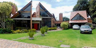 Amplia casa de dos niveles en conjunto cerrado, rodeada de jardines, en el primer nivel está la sala con chimenea, baño social, comedor , cuatro habitaciones, la principal con baño privado y vestier, baño auxiliar, estar de alcobas, en el segundo nivel se encuentra  el estudio y  la quinta habitación con su baño privado. En el primer nivel también está cocina con comedor auxiliar, lavandería , dos cuartos de servicio y un baño, dos depósitos y dos parqueaderos cubiertos. El conjunto cuenta con parqueaderos de visitantes. Cerca a colegios, centros comerciales , clínicas  y universidades. Vía Guaymaral, variante chía-cota, Av Pradilla.