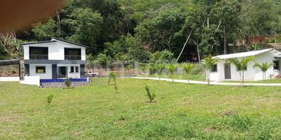 El Paraíso Que Soñaste Te Espera En Santa Fe De Antioquia
Imagina un lugar donde cada atardecer es una obra de arte y el clima perfecto te invita a vivir al máximo. Esta extraordinaria casafinca de 3.600 m² no es solo una propiedad, es el refugio ideal para tu familia y una oportunidad única para invertir en una zona de alta valorización. Ubicada estratégicamente sobre la nueva vía al Urabá, te ofrece lo mejor de dos mundos: un escape natural y una inversión con futuro garantizado.
La propiedad te recibe con una casa principal de 420 m² construidos, un espacio diseñado para el confort y el disfrute. Sus cinco habitaciones, cada una con su propio baño privado y clóset, garantizan la privacidad y comodidad que tú y tus invitados merecen. La cocina, moderna y con una isla central, es el corazón del hogar, ideal para crear momentos inolvidables. Además, cuenta con un amplio salón-comedor, baño social y zona de ropas independiente.
Afuera, la vida se convierte en una experiencia de descanso y diversión. La piscina de diseño moderno es el centro de tus días de sol, rodeada de zonas verdes, árboles frutales y un kiosko con baño para tus reuniones. Con un parqueadero para hasta 8 vehículos y una casa de mayordomo independiente, la comodidad está asegurada.