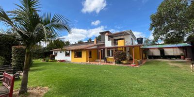 Atos Inmobiliaria vende exclusiva casa campestre en el municipio de Oicatá, a tan solo 20 minutos del casco urbano de Tunja. Esta hermosa propiedad de un nivel ofrece un ambiente tranquilo y natural, ideal para quienes buscan comodidad y calidad de vida en una zona rural con aire puro, amplias áreas verdes y un entorno seguro y familiar.

La casa cuenta con baño social, cocina integral con barra, sala y comedor independientes, sala de televisión, hall de alcobas y cinco habitaciones, incluyendo la principal con baño privado, además de dos baños de uso común. Dispone también de un altillo que funciona como amplio estudio con terraza y chimenea, otra chimenea en la sala, cuarto de ropas, espacio de almacenamiento y garaje cubierto para dos vehículos.

En el exterior encontrarás zonas verdes, parque infantil y espacios ideales para disfrutar en familia.

¡No esperes más! Contáctanos y agenda tu cita para adquirir la casa campestre de tus sueños.