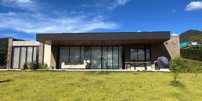 Vive el equilibrio perfecto entre elegancia, naturaleza y confort.
Esta espectacular residencia de lujo se encuentra en una exclusiva unidad cerrada del Oriente Antioqueño, a solo 10 minutos de La Ceja por la vía San Antonio. Rodeada de tranquilidad, paisajes verdes y un entorno campestre de alto nivel, esta propiedad redefine el concepto de bienestar.
•	Área del lote: 2.436 m²•	Área construida: 374 m² (incluye decks) •	Área verde libre: 1.861 m²
Distribución y acabados premium:
•	Habitación principal con vestier, baño privado y vista natural
•	2 habitaciones auxiliares, cada una con baño y closet
•	Baño social
•	Amplia sala-comedor con techos altos e iluminación natural
•	Cocina abierta con isla central, equipada con diseño moderno
•	Habitación de servicio con baño
•	Garaje cubierto para 2 vehículos
•	Jardinera interior con espejo de agua y fuentes, detalle arquitectónico único
•	Deck con zona BBQ ideal para reuniones y descanso
•	Vidrieras europeas y acabados modernos.